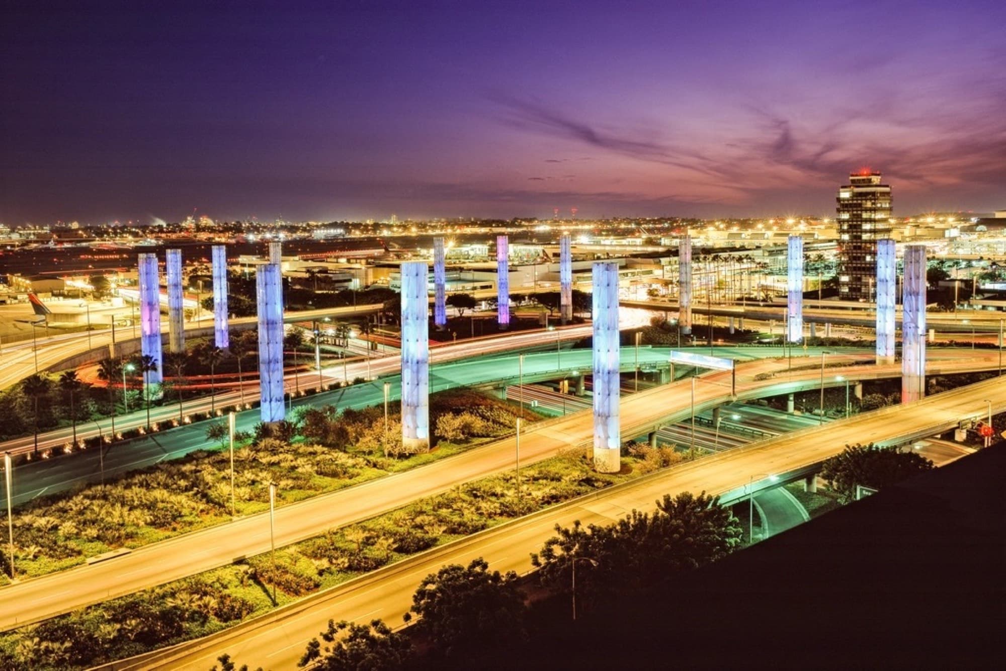 The lit pylons at the entrance to LAX at night